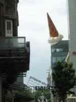 Sculpture of a very large ice cream cone inverted on top of a building