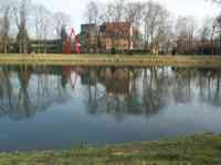 Buildings, sculpture, and trees reflecting in the Danube