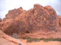 Red hill with black stuff and a cave