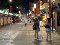 People on a street with lit stores and shop stalls